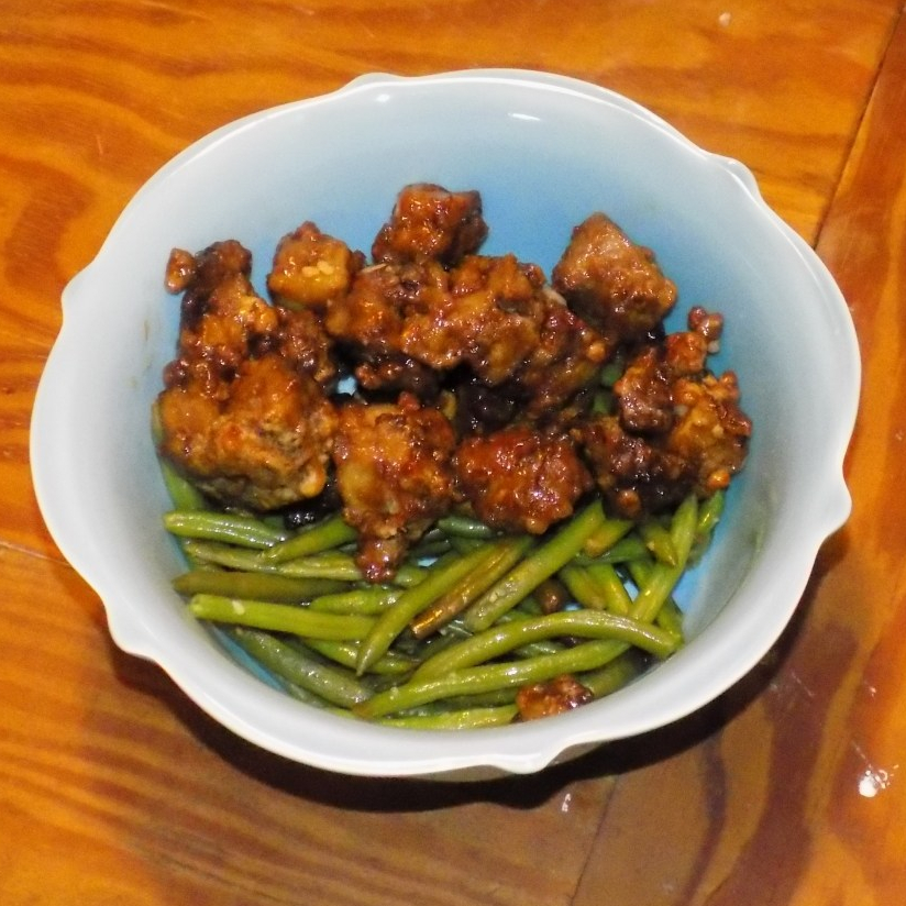 Cooked orange seitan in a bowl with green beans